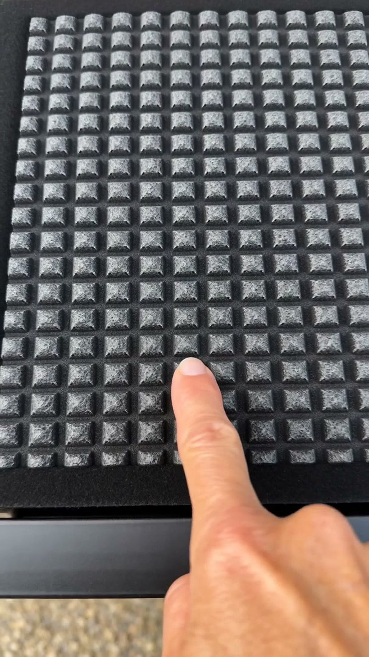 Close up of the raised non slip squares on the surface of the dog ramp, with a finger for scale