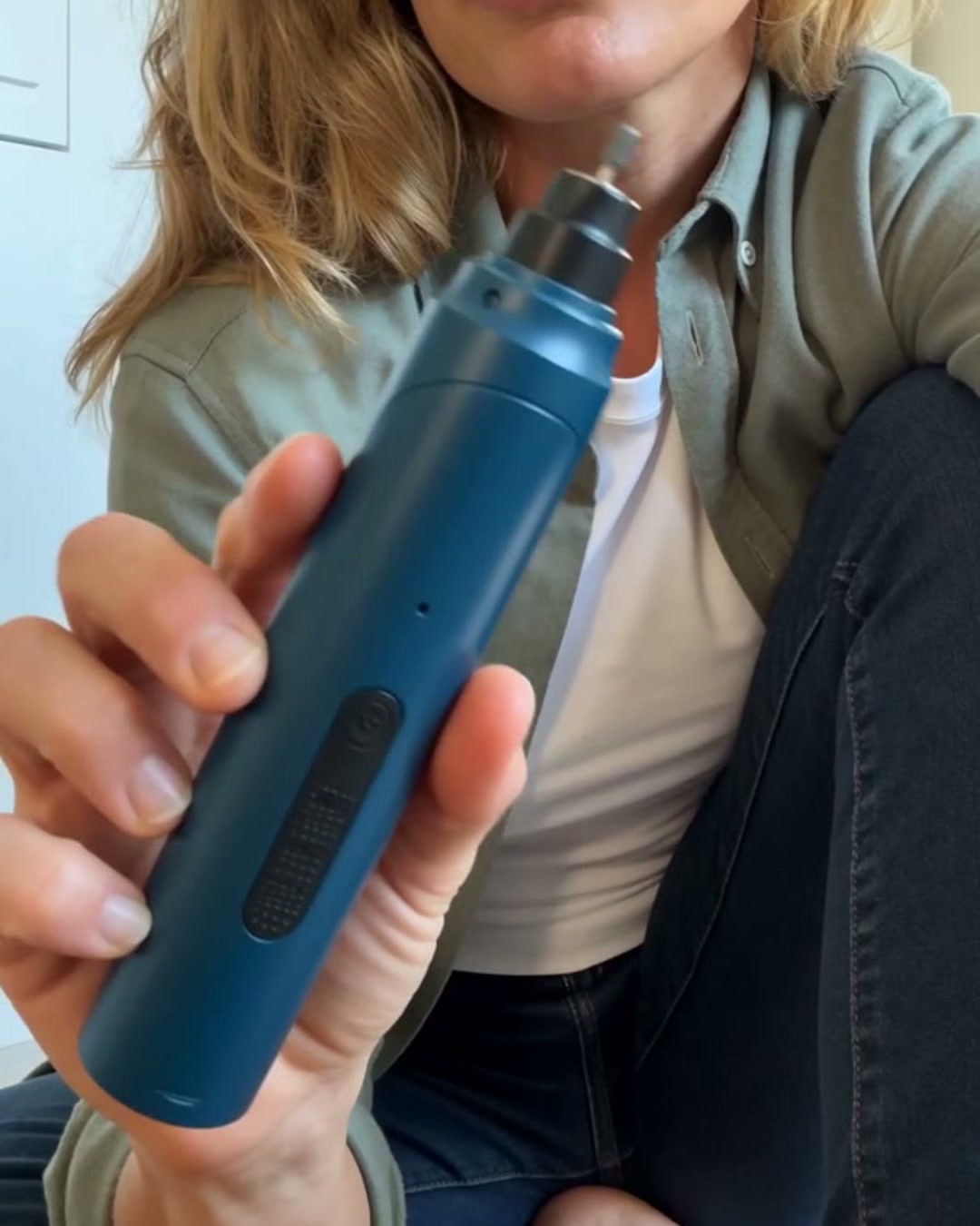 The quiet nail grinder held in one hand, sitting on the kitchen floor